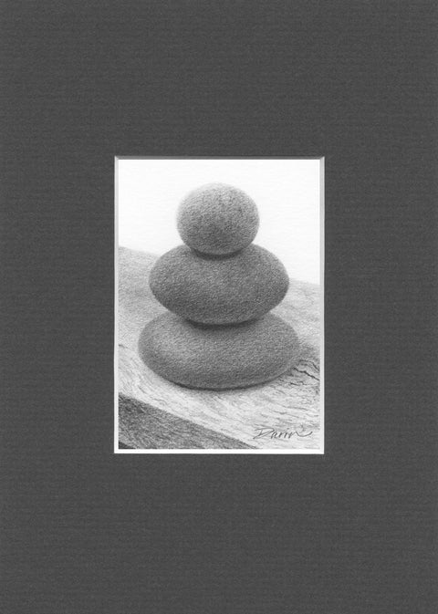A black and white graphite drawing of three stacked rounded stones, as a cairn, on a wood surface, with a visible artist signature ‘Darin’ near the bottom right, matted in charcoal-gray.