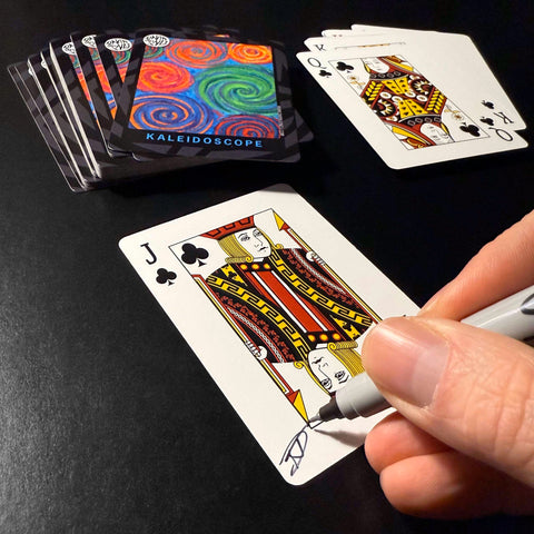 Back of the playing card showing the Jack of clubs with a hand‑signed signature ‘DJ’ in black ink.