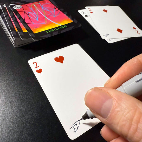 Back of the playing card showing the 2 of hearts with a hand‑signed signature ‘DJ’ in black ink.