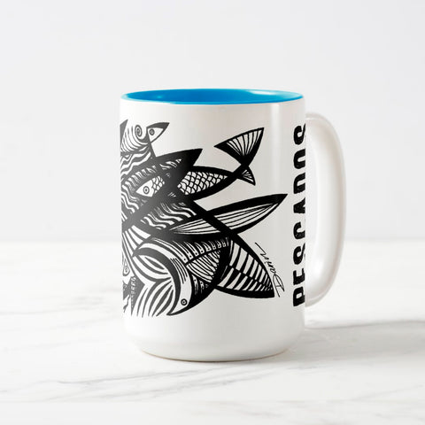 White ceramic coffee mug with a white handle and blue interior, featuring a wrap‑around print of the artwork titled “Pescados.“