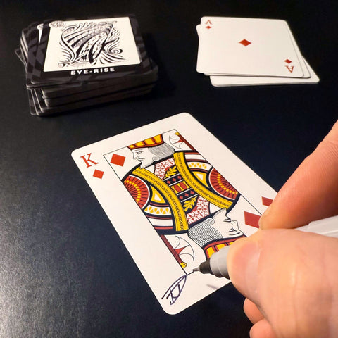 Back of the playing card showing the King of diamonds with a hand‑signed signature ‘DJ’ in black ink.