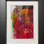 Abstract textured painting with layered brush and palette-knife strokes in bold red, magenta, green, yellow, orange, and black; matted in white and framed in black.