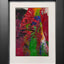 Abstract textured painting with layered brush and palette-knife strokes in bold red, green, yellow, purple, and black; matted in white and framed in black.