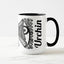 White ceramic coffee mug with a black handle and black interior, featuring a wrap‑around print of the artwork titled “Burnin’ Urchin.“