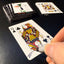 Back of the playing card showing the Queen of clubs with a hand‑signed signature ‘DJ’ in black ink.