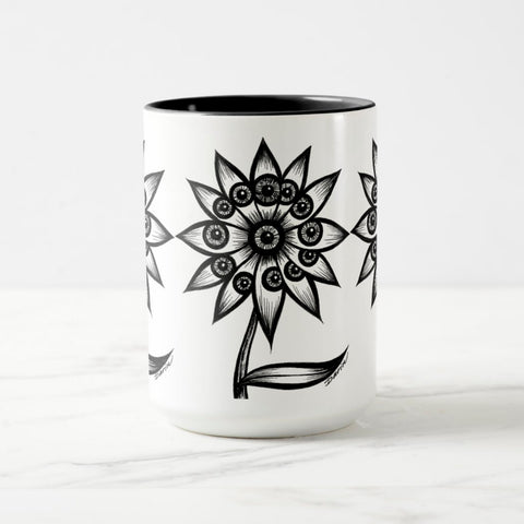 White ceramic coffee mug with a black handle and black interior, featuring a wrap‑around print of the artwork titled “Flowerize.“
