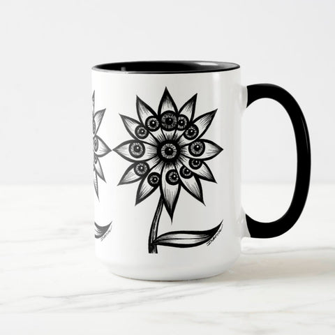 White ceramic coffee mug with a black handle and black interior, featuring a wrap‑around print of the artwork titled “Flowerize.“