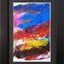 Abstract textured painting with layered brush and palette-knife strokes in blue, red, pink, yellow, brown, and white; matted and framed in black.