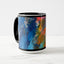 White ceramic coffee mug with a black handle and black interior, featuring a wrap‑around print of the artwork titled “Jubilation Palette.“