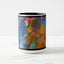 White ceramic coffee mug with a black handle and black interior, featuring a wrap‑around print of the artwork titled “Jubilation Palette.“