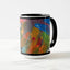 White ceramic coffee mug with a black handle and black interior, featuring a wrap‑around print of the artwork titled “Jubilation Palette.“