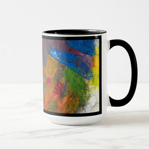 White ceramic coffee mug with a black handle and black interior, featuring a wrap‑around print of the artwork titled “Jubilation Palette.“