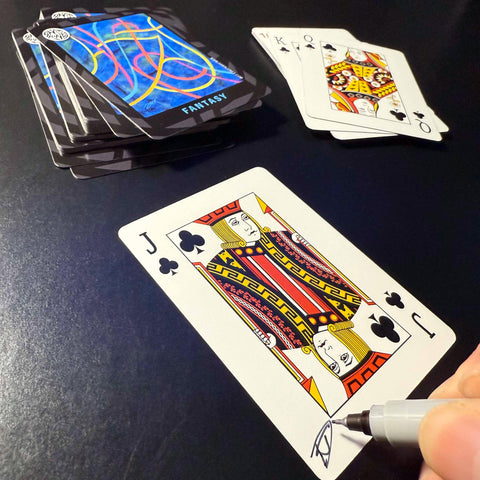 Back of the playing card showing the Jack of clubs with a hand‑signed signature ‘DJ’ in black ink.