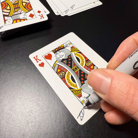 Back of the playing card showing the King of hearts with a hand‑signed signature ‘DJ’ in black ink.