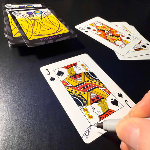 Back of the playing card showing the Jack of spades with a hand‑signed signature ‘DJ’ in black ink.