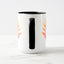 White ceramic coffee mug with a black handle and black interior, featuring a mirrored colorful gradient print of the artwork titled “Pinned.“