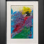 Abstract textured painting with layered brush and palette-knife strokes in blue, purple, yellow, black, red, and green; matted in white and framed in black.