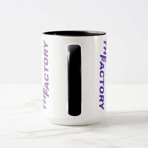 White ceramic coffee mug with a black handle and black interior, featuring a wrap‑around print of the artwork titled “The Factory.“