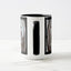 A white ceramic coffee mug with a black handle and black interior, focusing on the handle, with the beginning and end sections of a wrap-around photographic print of a wet street plate with the word ‘WATER’. 